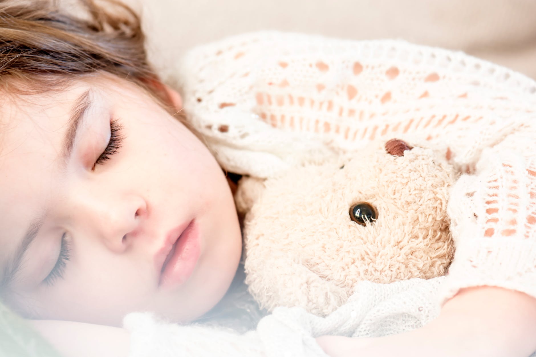 Image of a sleeping toddler with a soft bear